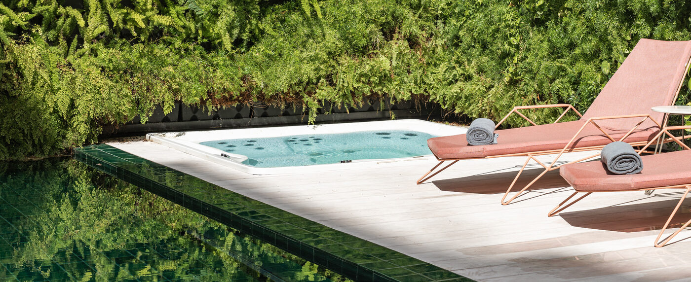 The outdoor pool at Luster Hotel Lisbon with pink sun loungers and lush green walls