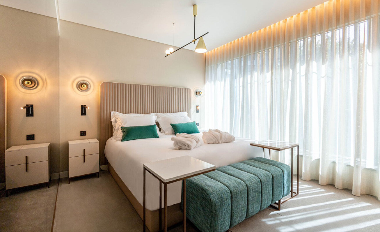 A stylish guest room at Luster Hotel Lisbon with teal accents and mid-century inspired lighting