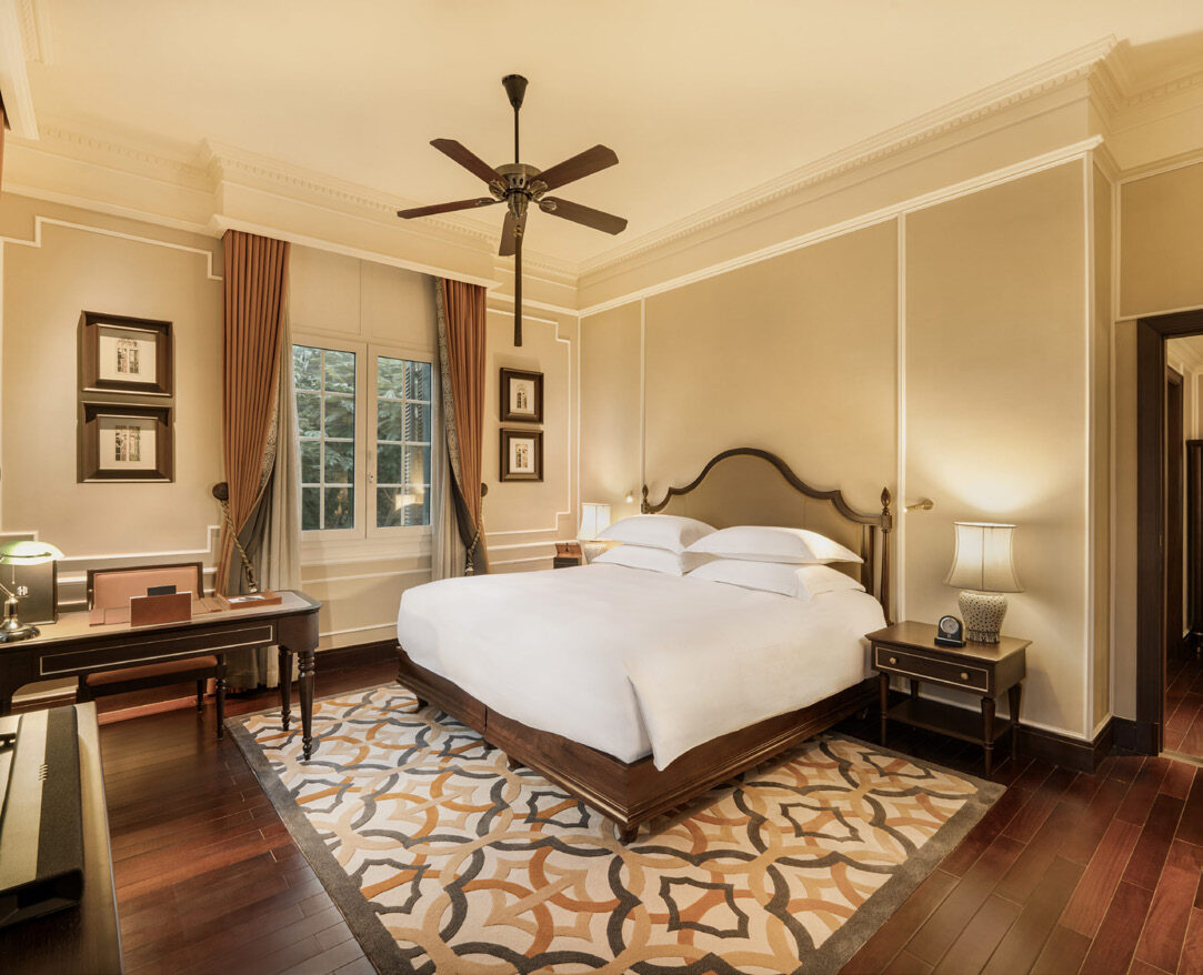 A grand suite at Sofitel Legend Metropole Hanoi with dark wood floors, ceiling fan and elegant period furnishings