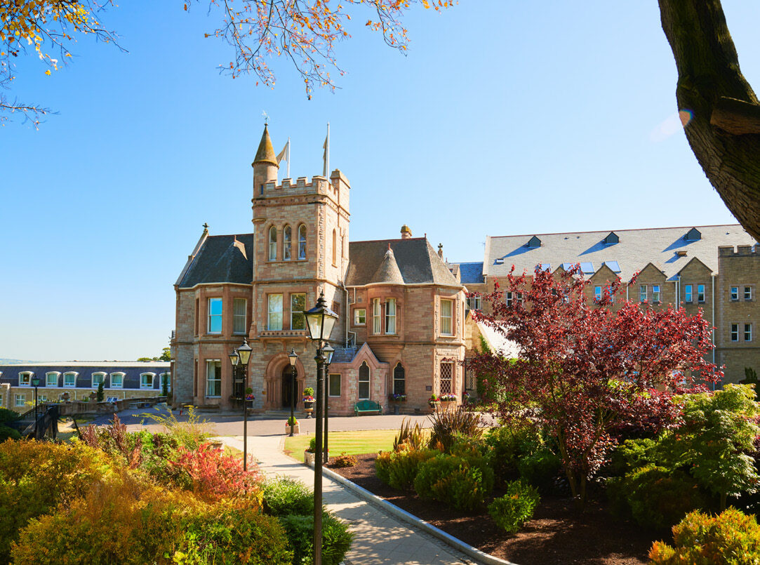 The Scottish Baronial exterior of Culloden Estate and Spa surrounded by autumn foliage in Northern Ireland