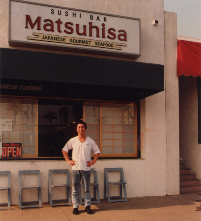 A young Nobu Matsuhisa standing outside his Matsuhisa Sushi Bar restaurant in Los Angeles