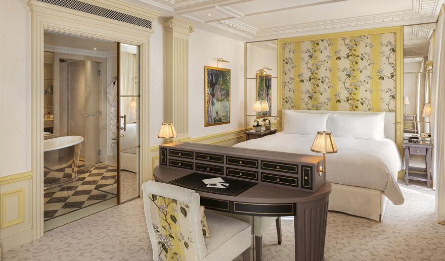 Elegant guest room at Hôtel Métropole Monte-Carlo with yellow floral wallpaper, writing desk and en-suite bathroom