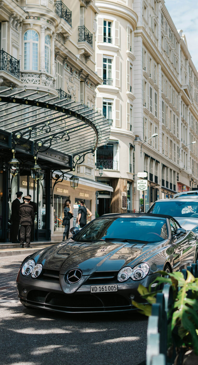 A luxury Mercedes sports car parked on an elegant Monaco street lined with designer boutiques