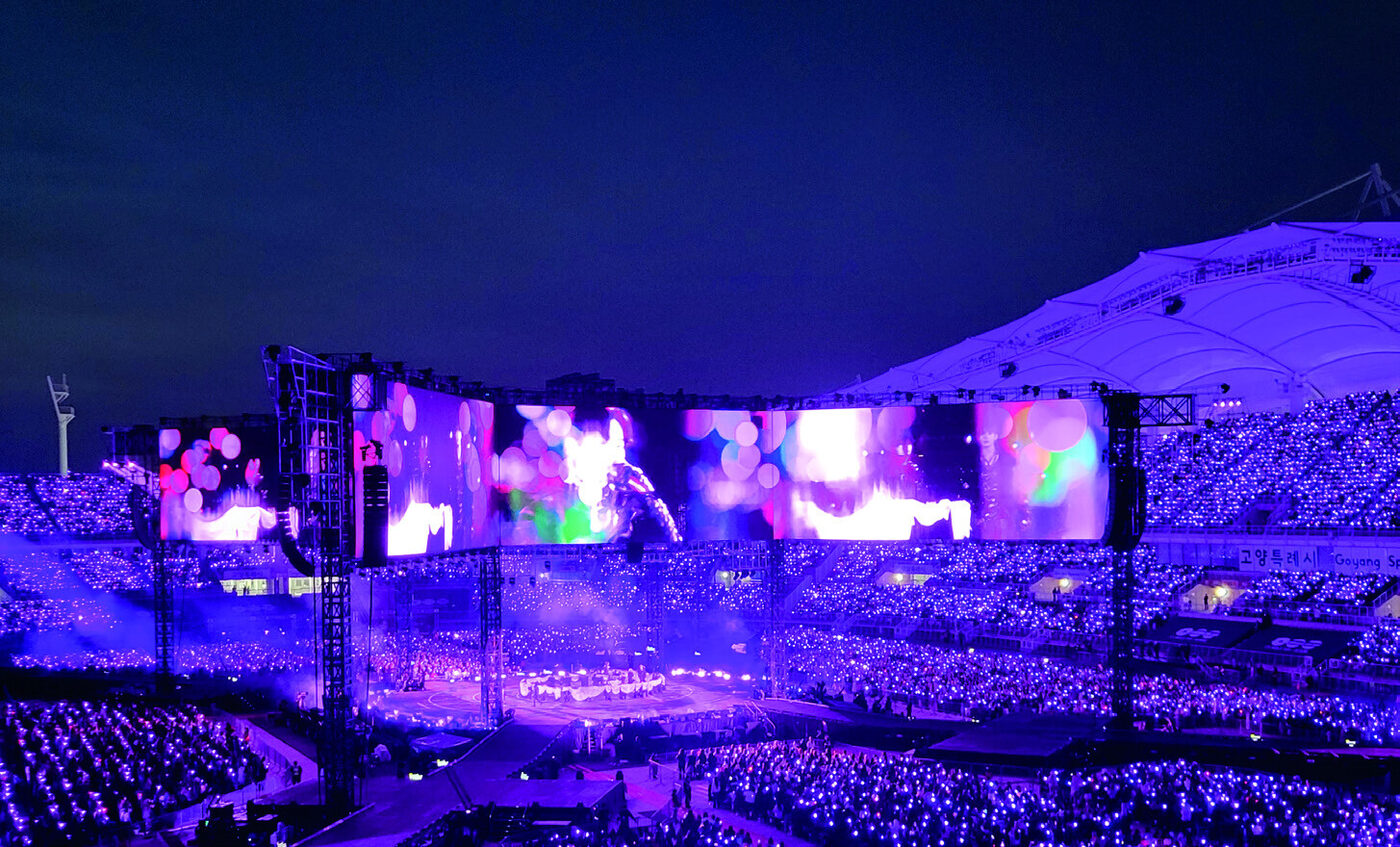 A spectacular K-pop concert at a packed stadium in South Korea, lit up in purple light