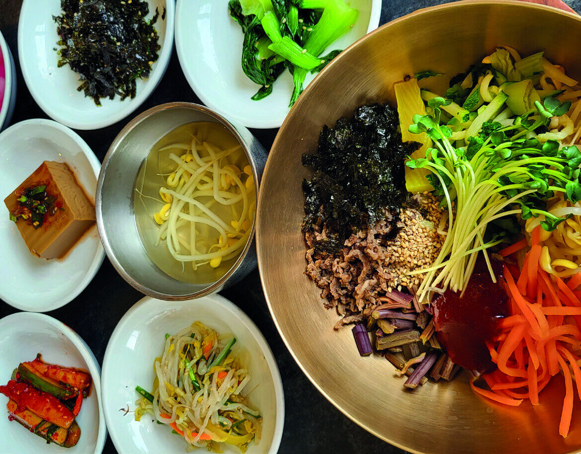 A spread of Korean bibimbap with colourful vegetable side dishes and soup